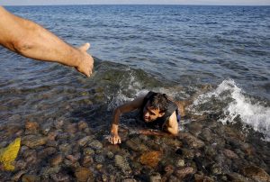 PHOTO: A local man helps a Syrian refugee swimming exhaustedly from a dinghy to a Lesbos beach, Sept. 17, 2015.Yannis Behrakis / Reuters